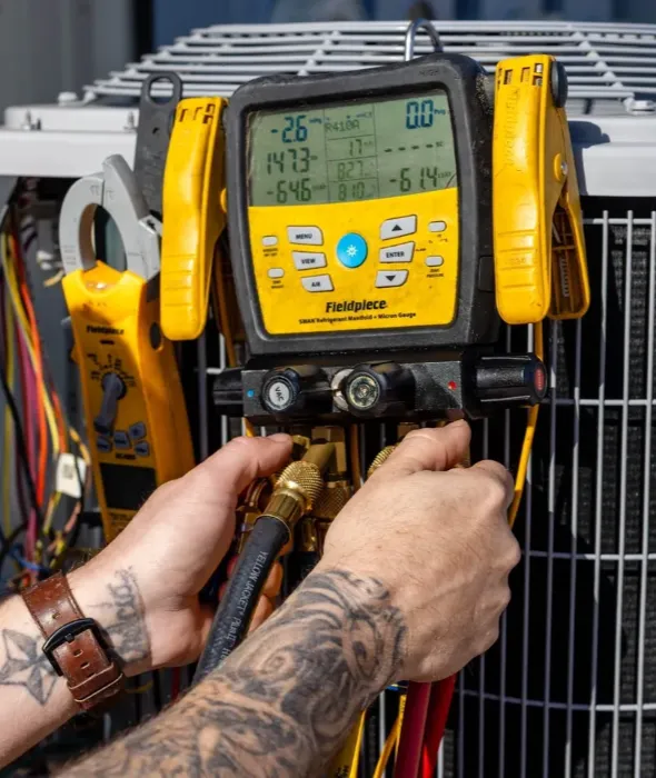 Technician connecting HVAC manifold gauges to condenser