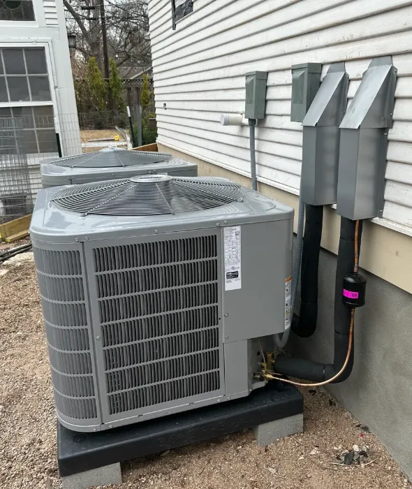 Two outdoor HVAC condenser units beside house